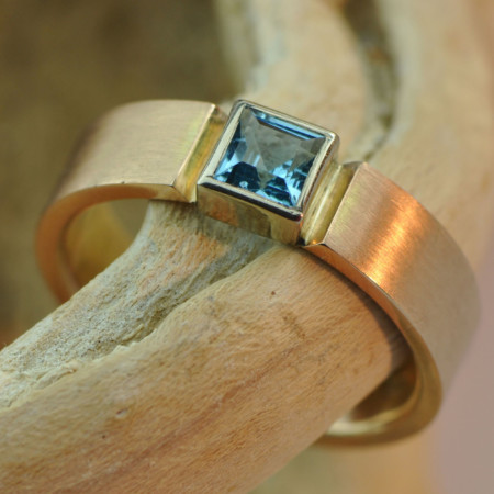 Gouden ring met topaas: roodgouden ring met vierkante blauwe topaas