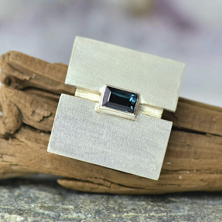 Zilveren broche met blauwe toermalijn, mat zilver, broche voor op jasje of trui, handgemaakt door LYAM edelsmeden, unieke vormgeving