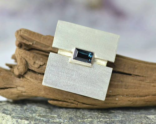 Zilveren broche met blauwe toermalijn, mat zilver, broche voor op jasje of trui, handgemaakt door LYAM edelsmeden, unieke vormgeving