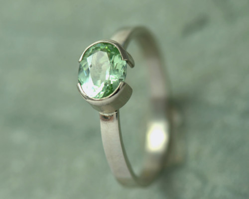 Witgouden ring met mintgroene peridoot: ovale groene edelsteen peridoot is gezet op een witgouden ringband. Halfopen zetting. Handgemaakt.